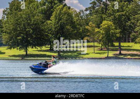 Lady che cavalca la moto d'acqua e trascorre una giornata d'estate sul lago Oconee, Georgia. L'equitazione di moto d'acqua personale è una forma popolare di attività ricreative acquatiche. Foto Stock