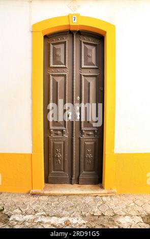 Ferragudo, Portogallo - 20 ottobre 2022: Facciata imbiancata con porta in legno colorata nella città di Ferragudo, Portogallo Foto Stock