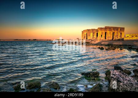 Sunrise drammatica con acqua setosa vista Al uqair rovinato fort lato mare Arabia Saudita. Foto Stock