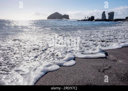 Onde schiumose del mare sulla spiaggia di sabbia al mattino. Spiaggia di Mosteiros nell'isola di Sao Miguel nelle Azzorre. Foto Stock