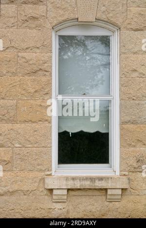Finestra ad arco con copertura Keystone incastonata in una parete calcarea Foto Stock