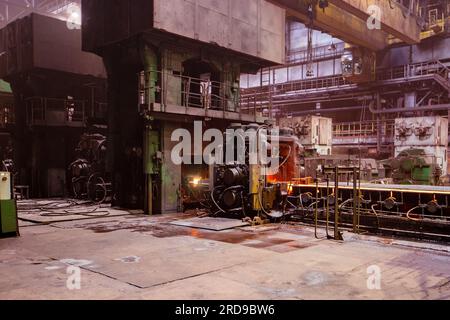 Barra in acciaio caldo di fabbrica di metalli laminati sul trasportatore che si muove attraverso i rulli. Foto Stock