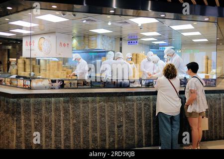 Gli ospiti guardano il personale della cucina mentre preparano gnocchi, bao e altri dim sum cinesi al ristorante DIN Tai Fung al centro commerciale Taipei 101 a Taipei, Taiwan. Foto Stock