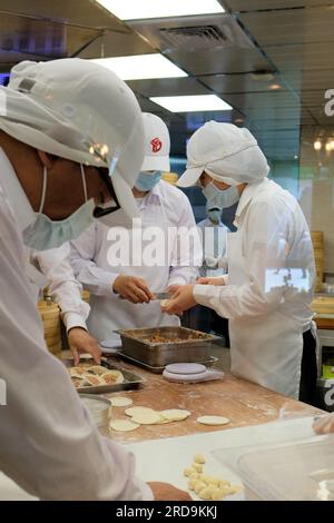 Cuochi e personale di cucina preparano gnocchi, bao e altri dim sum cinesi al ristorante DIN Tai Fung al centro commerciale Taipei 101 a Taipei, Taiwan. Foto Stock