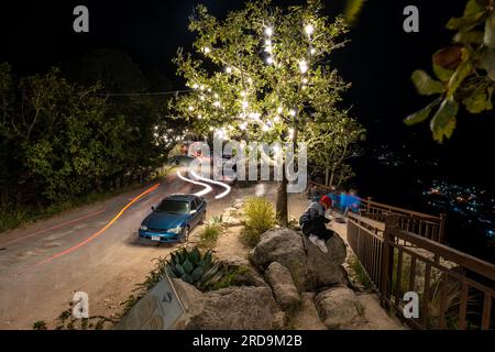 Tegucigalpa, Francisco Morazan, Honduras - 11 dicembre 2022: Long Exposure Shot of a Car Parked, a Tree in 'El Picacho' Park with White Light Garland Foto Stock