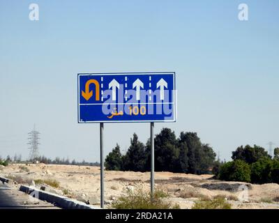Traduzione del testo arabo (100 M cento metri) a lato di un cartello segnaletico informativo che mostra 4 corsie e indirizza i conducenti verso un u t Foto Stock