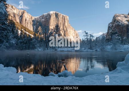 Impressione delle montagne che circondano la Valle di Yosemite, durante l'ora d'oro, che si riflettono nel fiume Merced. Foto Stock