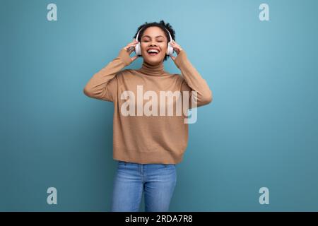 sfondo isolato, giovane bruna, freelance ispanica che ascolta musica con le cuffie bluetooth Foto Stock