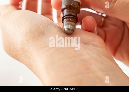 mani di donna che testano un rotolo con olio essenziale , applicando liquido al polso, messa a fuoco morbida Foto Stock