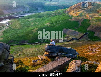 Uomo che si gode il tramonto sulla cima di una roccia Foto Stock