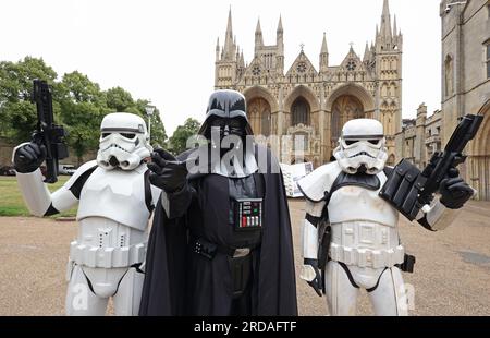 Peterborough, Regno Unito. 18 luglio 2023. Darth Vadar e Stormtroopers si posano fuori dalla Cattedrale di Peterborough prima che una delle più grandi collezioni private di fan di Star Wars al mondo possa essere vista nella magnifica Cattedrale di Peterborough dal 19 luglio. La mostra, galassie non ufficiali, presso la Cattedrale di Peterborough, comprende oltre 120 mostre, con un Land Speeder a grandezza naturale in mostra insieme a giocattoli e oggetti rari di Star Wars. Peterborough, Cambridgeshire, Regno Unito. Credito: Paul Marriott/Alamy Live News Foto Stock