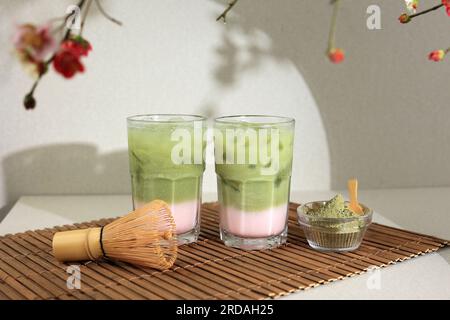 Due bicchieri di latte Matcha freddo con latte di fragola in vetro alto su fondo crema Foto Stock