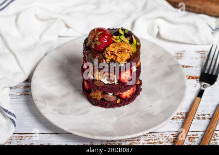 Strato di torta. Fragole, pistacchio, crocchant e torta con panna su fondo di legno Foto Stock