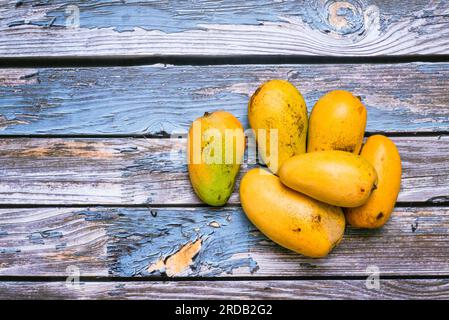 Gruppo di mango maturi in ambiente scuro su tavola di legno. Vista dall'alto. Foto Stock