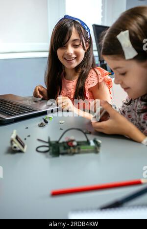 Studentessa felice sorridente mentre cerca di comporre pezzi di macchina Foto Stock