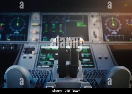 Primo piano della cabina di pilotaggio di un aereo commerciale. Attenzione selettiva alle leve di spinta del motore contro il pannello di controllo illuminato del piano moderno. Foto Stock