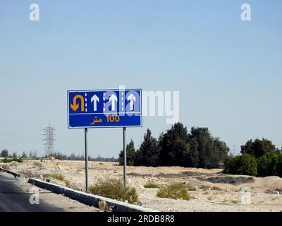 Traduzione del testo arabo (100 M cento metri) a lato di un cartello segnaletico informativo che mostra 4 corsie e indirizza i conducenti verso un u t Foto Stock