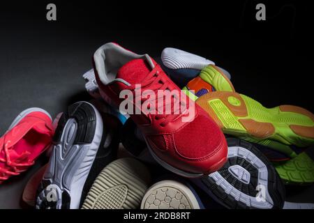 Le sneaker multicolore sono impilate su uno sfondo grigio. Scarpe sportive. Foto Stock