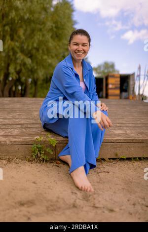 donna che aspetta il noleggio dell'attrezzatura seduto su un argine di legno. inviti a correre insieme Foto Stock