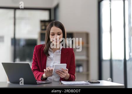 Donna d'affari che utilizza una calcolatrice per controllare le finanze aziendali, i guadagni e il budget. Donna d'affari che calcola le spese mensili e gestisce il budget Foto Stock