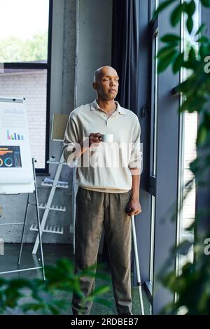 malattia cronica, inclusione, uomo afro-americano con miastenia grave malattia tenendo tazza di caffè, audace e scuro pelle ufficio lavoratore in casual a Foto Stock