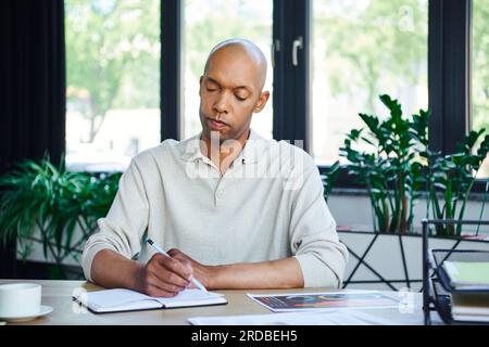 uomo con sindrome da ptosi prendendo appunti, audace uomo d'affari afro-americano al lavoro, lavoratore d'ufficio dalla pelle scura con miastenia grave malattia, diversità Foto Stock