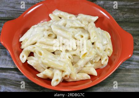 Piatto classico gustoso e appetitoso di penne di macaroni con salsa bianca, aglio, cipolla, spezie, olio e pepe nero, selezione di una costoletta italiana Foto Stock