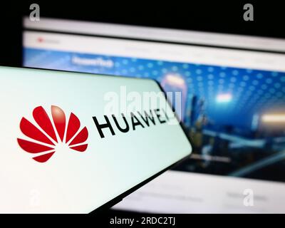 Telefono cellulare con logo della società cinese Huawei Technologies Co. Ltd. Sullo schermo davanti al sito Web. Mettere a fuoco il display centrale sinistro del telefono. Foto Stock