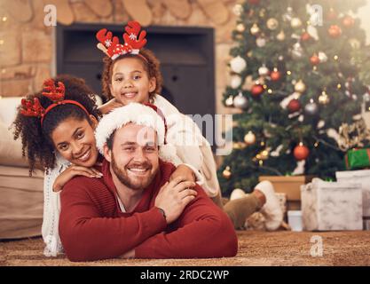 Natale, ritratti e famiglia felice in casa sul pavimento, incollaggio e insieme. Natale, sorriso e volto dei genitori con bambino, interrazziale e africano Foto Stock