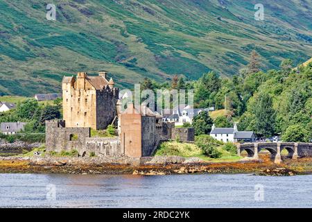 Eilean Donan Castle Loch Duich Dornie costa occidentale della Scozia con case di villaggio e vista sull'acqua in estate Foto Stock