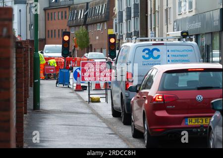 Auto e veicoli in coda o in attesa ai semafori rossi temporanei su una strada britannica durante i lavori stradali in una trafficata città, nel Regno Unito. Foto Stock