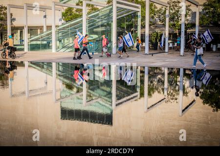 Tel Aviv, Israele. 18 luglio 2023. I manifestanti hanno la bandiera israeliana mentre si riuniscono per una manifestazione a Tel Aviv. Decine di migliaia di manifestanti martedì hanno bloccato autostrade e stazioni ferroviarie e hanno marciato nel centro di Tel Aviv durante una giornata di manifestazioni a livello nazionale contro il controverso piano di revisione giudiziaria del primo ministro Benjamin Netanyahu. Credito: SOPA Images Limited/Alamy Live News Foto Stock