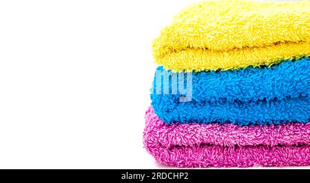 Primo piano di tre asciugamani da bagno di diversi colori impilati su uno sfondo bianco. Foto Stock