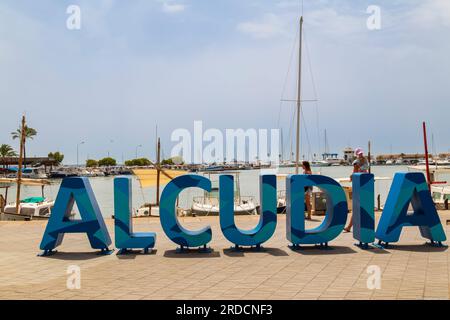 Cartello con grandi lettere blu che leggono Alcudia, sul lungomare della località di Alcúdia, nel nord dell'isola mediterranea di Maiorca in Spagna. Foto Stock