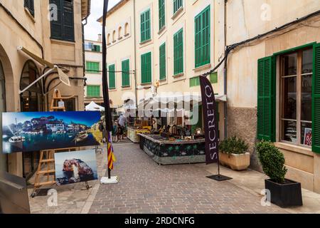 Le persone passeggiano lungo una stradina intima fiancheggiata da bancarelle di merci nella pittoresca cittadina di Santanyí, sull'isola mediterranea di Maiorca, a SP Foto Stock