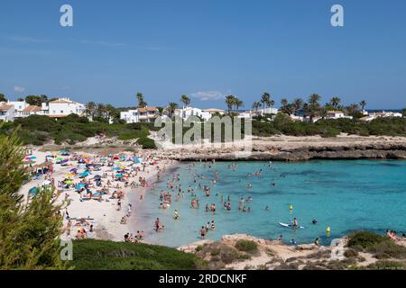 I turisti si godono l'acqua di mare nella località di Cala en Bosc sull'isola spagnola di Minorca. Foto Stock