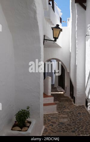 Stretta strada con case bianche nel pittoresco villaggio di Binibequer sull'isola spagnola di Minorca. Foto Stock