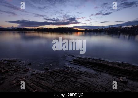 I colori caldi sbiadono all'ora blu mentre il sole scende sotto l'orizzonte sul lago Lanier. Foto Stock