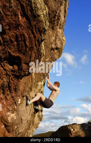 Un giovane che sale su Agglestone Rock. La roccia è anche conosciuta come The devil's Anvil. Foto Stock