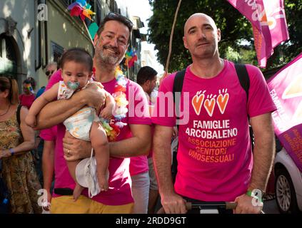 Un paio di uomini con figlia adottiva, sorridenti davanti alla telecamera, durante la sfilata LGBTQ del Toscana Pride. Foto Stock