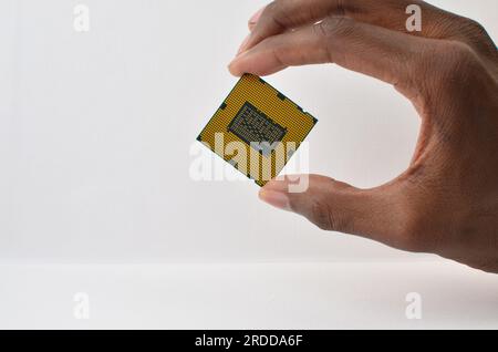 Primo piano di una mano che regge un processore di computer, simboleggia la potenza di elaborazione e l'innovazione. Foto Stock