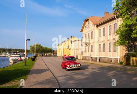 Amal, Svezia - 25 maggio 2023: Un'auto Volvo rossa d'epoca percorre la strada della città vecchia di Amal e vicino al porticciolo Foto Stock