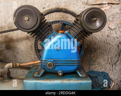 Fotografia ravvicinata del motore molto usato di un compressore d'aria scattato in un'officina di auto nella città di Arcabuco, nella Colombia centrale. Foto Stock