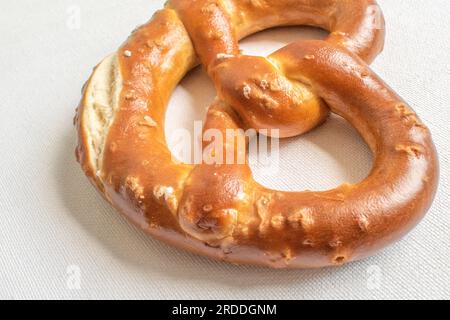 Soffice pretzel appena sfornato con una spolverata di sale, offre una deliziosa combinazione di morbidezza e sapore saporito. Presentato su sfondo bianco f Foto Stock