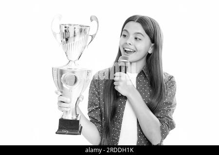 Ragazza adolescente con la tazza di vincita. Teen che tiene un discorso del microfono del trofeo. Bambino vincitore del capretto ha vinto la concorrenza, celebrando il successo e la vittoria. Foto Stock