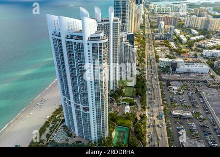 Alti e costosi hotel e condomini sulla costa dell'oceano Atlantico nella città di Sunny Isles Beach e trafficato traffico stradale. Infrastrutture turistiche americane a sou Foto Stock