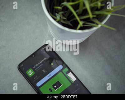 LOD, Israele - 16 luglio 2023: Area di lavoro moderna con smartphone con app Unified Remote, pagina Play Store su sfondo marmoreo. Vista dall'alto ravvicinata, posizionamento piatto. Foto Stock