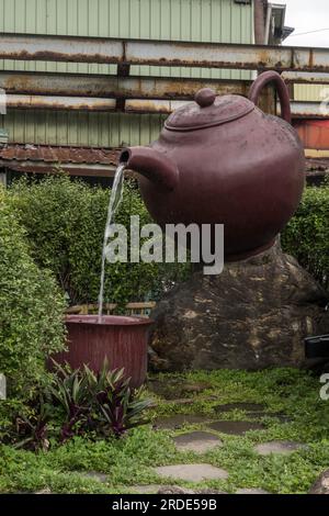 Teiera gigante che versa il tè in un grande bicchiere da tè a Pinglin, Taipei, Taiwan. Foto Stock