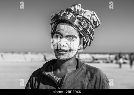 Morondava, Madagascar - 31 maggio 2023: Una donna malgascia con maschera pittorica, è conosciuta come Masonjaony sulla costa di Morondava, bianco e nero Foto Stock