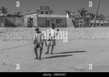 Morondava, Madagascar - 31 maggio 2023: Due uomini tirano una corda per pescare sulla costa da Morondava, bianco e nero Foto Stock